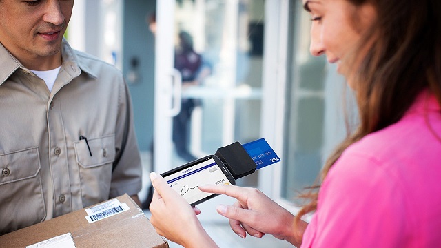 Woman signing for package using Square Reader on smart phone with her Visa card for payment. Woman signing for package using Square Reader on smart phone with her Visa card for payment.