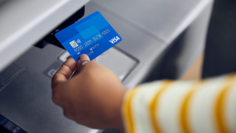A hand tapping a Visa card with Visa's contactless payments system.
